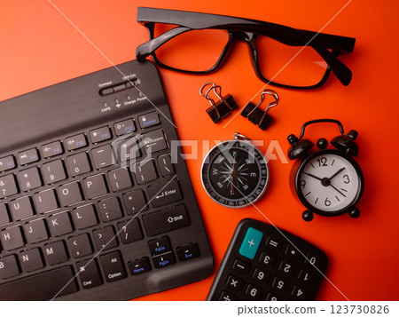 Keyboard,clock,calculator,compass and glasses on a orange background.Business concept. 123730826