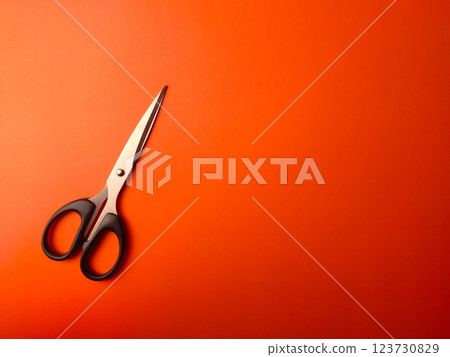 Top view black scissors on an orange background with copy and text space. Top view black scissors on an orange background with copy and text space. 123730829