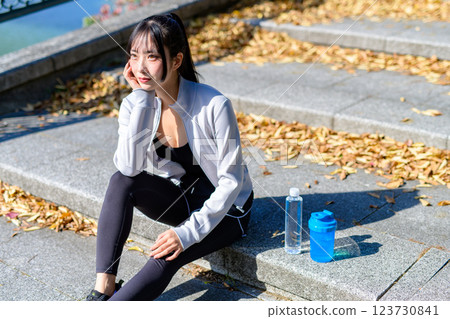 A cool woman sitting down and taking a break while walking along a riverside road Exercise Aerobic exercise Walking A cool woman sitting down and taking a break while walking along a riverside road Exercise Aerobic exercise Walking 123730841