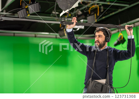 Boom microphone operator testing sound at TV studio. Boom microphone operator testing sound at TV studio. 123731308