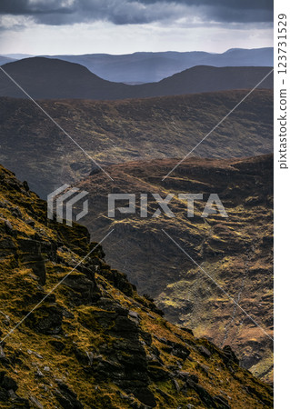 Majestic mountains create a dramatic backdrop of rolling hills and rugged terrain under clear skies. Sunlight enhances the natural beauty of the landscape. Majestic mountains create a dramatic backdrop of rolling hills and rugged terrain under clear skies. Sunlight enhances the natural beauty of the landscape. 123731529