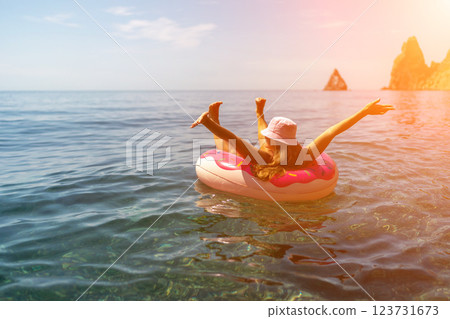 Summer vacation woman in hat floats on an inflatable donut mattress. Happy woman relaxing and enjoying family summer travel holidays travel on the sea. 123731673