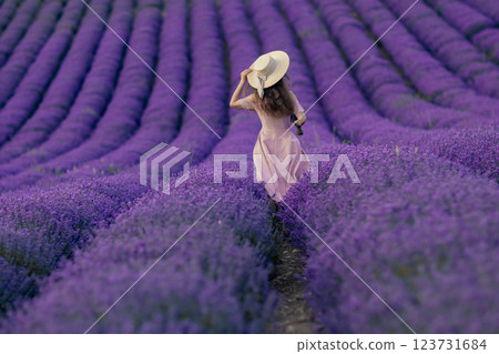 A woman is walking through a field of purple flowers A woman is walking through a field of purple flowers 123731684