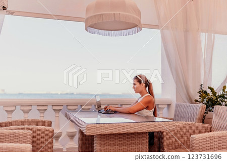 Woman coffee cafe laptop sea. Female freelancer using laptop on coffee break in modern cafe with sea view in the morning Woman coffee cafe laptop sea. Female freelancer using laptop on coffee break in modern cafe with sea view in the morning 123731696