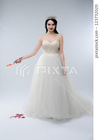 Bride in elegant lingerie with a bloodied knife creates a haunting scene 123732020