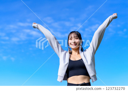 A cool woman pumping her fist in the blue sky while walking Workout Trimming 123732270