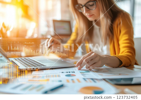 Businesswoman Analyzing Financial Reports with Laptop in Modern Office Setting During Daytime Businesswoman Analyzing Financial Reports with Laptop in Modern Office Setting During Daytime 123732405