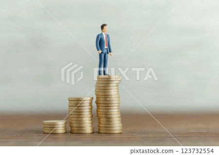 Creative Businessman on Top of Coins Representing Financial Success and Growth Creative Businessman on Top of Coins Representing Financial Success and Growth 123732554