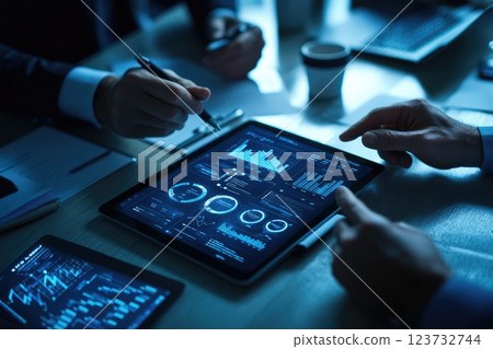 A group of people are looking at a tablet with graphs on it 123732744