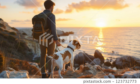 A man and his dog are walking along a rocky beach at sunset 123732773