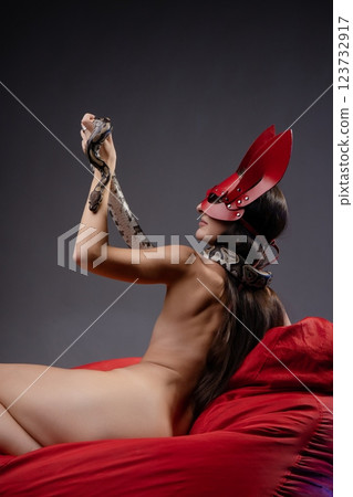 Sensual woman poses with a snake while wearing striking headpiece Sensual woman poses with a snake while wearing striking headpiece 123732917
