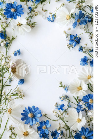 Wild blue and white flowers arranged in a playful, chaotic pattern around an empty space for text, set against a simple white background, creating a minimalist and fresh vibe 123732990