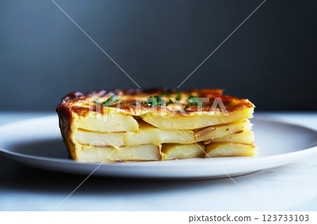 A classic Spanish tortilla, golden and crispy on the outside, filled with soft potatoes, onions, and eggs, garnished with fresh parsley and served with crusty bread, traditional Spanish dish 123733103