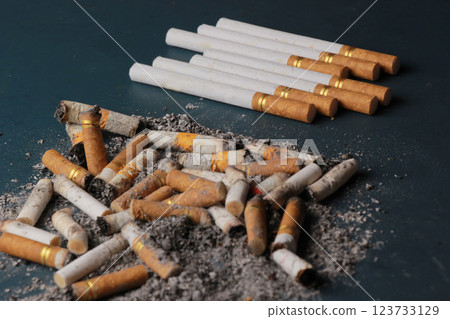 Dirty cigarette butts with stack of cigarettes, plain turquoise isolated. blur. 123733129