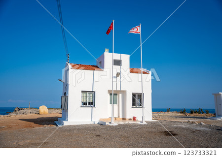 Small white building at the northeasternmost cape of Cyprus with the flags of Turkey and Northern Cyprus. Islands farthest point and serves as a symbol of political and territorial presence 123733321