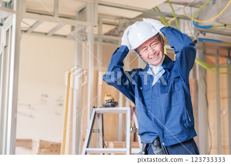 Male carpenter holding his head at the construction site Male carpenter holding his head at the construction site 123733333
