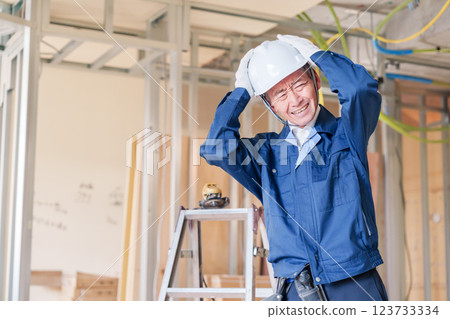 Male carpenter holding his head at the construction site Male carpenter holding his head at the construction site 123733334