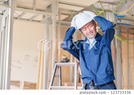 Male carpenter holding his head at the construction site 123733336