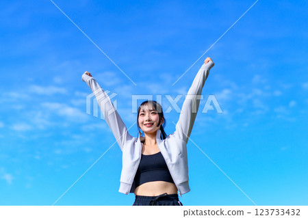 A cool woman pumping her fist in the blue sky while walking Workout Trimming 123733432