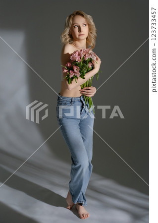 Woman holding flowers poses gracefully against a soft backdrop Woman holding flowers poses gracefully against a soft backdrop 123733457
