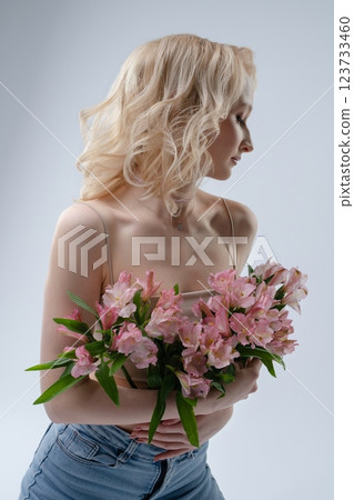 Model with flowers poses gracefully against a plain background Model with flowers poses gracefully against a plain background 123733460