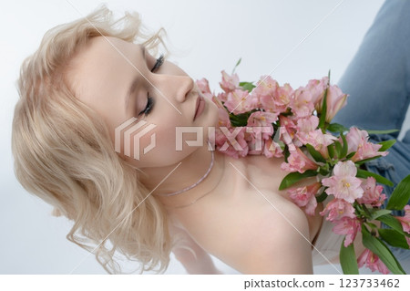 Model poses gracefully with pink flowers in a studio setting Model poses gracefully with pink flowers in a studio setting 123733462