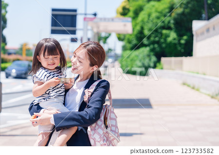A working mother taking her child to nursery school before work A working mother taking her child to nursery school before work 123733582