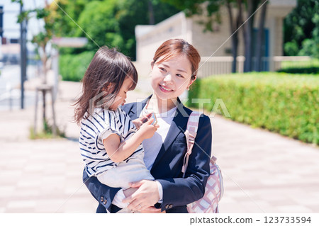 A working mother taking her child to nursery school before work A working mother taking her child to nursery school before work 123733594