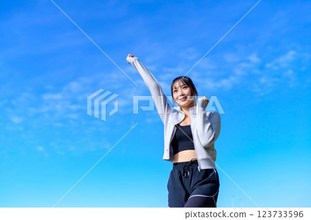 A young woman doing a cute fist pump towards the blue sky while walking Workout A young woman doing a cute fist pump towards the blue sky while walking Workout 123733596