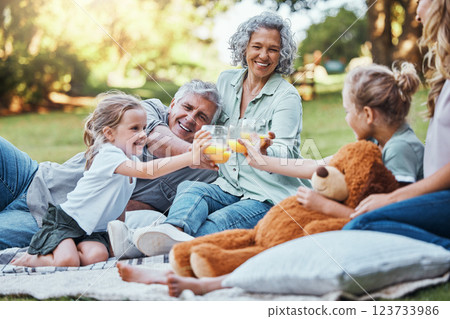 Family, cheers with juice and a picnic in park on happy summer weekend with smile. Grandma, grandpa and mother with girl children relax, celebrate outdoor fun and quality time together in Australia. 123733986