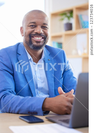 Happy, smile and portrait of an African businessman sitting at his desk and working on a laptop in his office. Happiness, leader and black man leader planning management documents on computer. 123734016