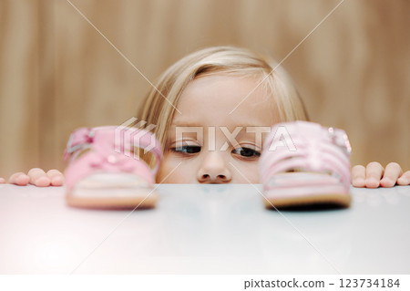 Kids, fashion and shoes with a girl choosing between footwear while shopping in a retail store. Children, cute and choice with a young female child deciding what shoe to buy for her home wardrobe 123734184