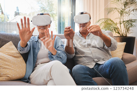 Senior couple and vr technology for metaverse retirement fun and futuristic simulation in home. Married people enjoy 3d virtual reality glasses experience for leisure entertainment on sofa. 123734248