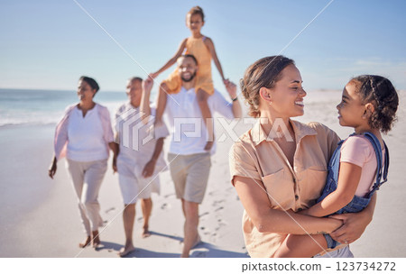 Mother and child on holiday by the beach with grandparents taking a walk together. A happy big family walking by the sea and mom and dad carrying kids. Summer, vacation and family fun by the ocean 123734272