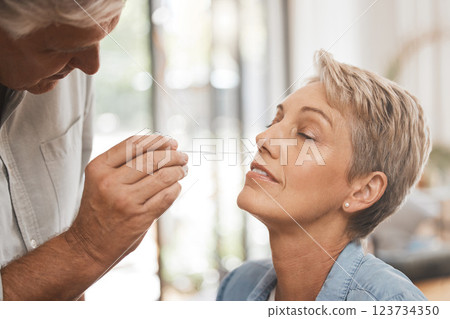 Covid, healthcare and test with a woman and man doing a nasal swab in the home for pcr testing. Medical, care and insurance with a senior couple in a house during the corona virus pandemic 123734350