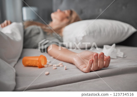 Depression, mental health and overdose with pills and woman in bedroom for anxiety, suicide and death. Sad, medicine and grief with girl lying in bed after taking drugs for pain, trauma and problem 123734516