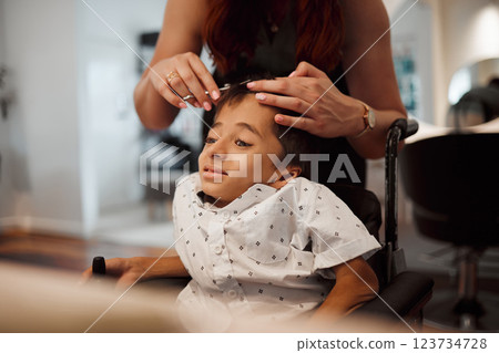 Hairdresser, child with disability and wheelchair with hairstylist cutting his hair at salon. Young kid with cerebral palsy in Mexico getting professional haircut with scissors from beautician woman 123734728