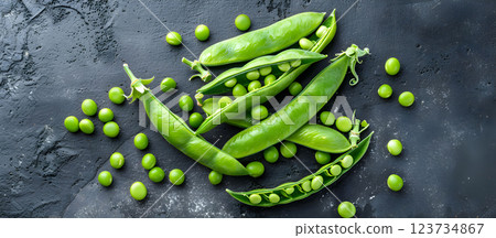 Fresh green peas and pods arranged on a dark surface showcasing vibrant colors and textures for a healthy culinary backdrop 123734867