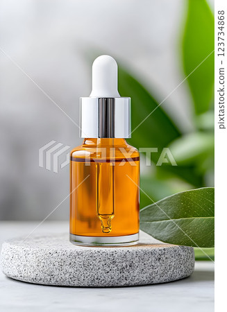 Elegant bottle of cosmetic serum on a stone surface with green leaves, ideal for spa and aromatherapy applications 123734868
