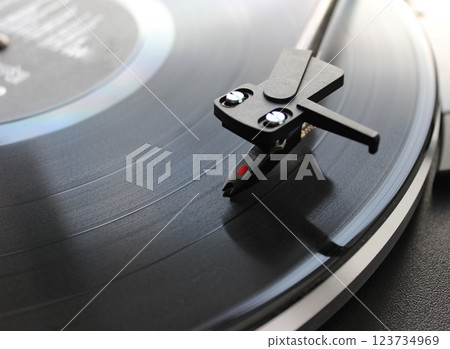 Head Of Vinyl Record Player On Disc In Front Of Defocused Black Headphones On White Background 123734969
