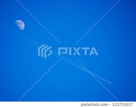 Half moon and a plain trail in a day sky Half moon and a plain trail in a day sky 123735827