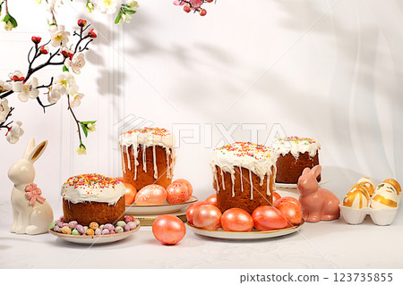 Happy Easter concept. Abstract Easter composition with traditional Russian kulich with meringue and decorated eggs on elegant kitchen table with spring sakura flowers. Screen banner 123735855