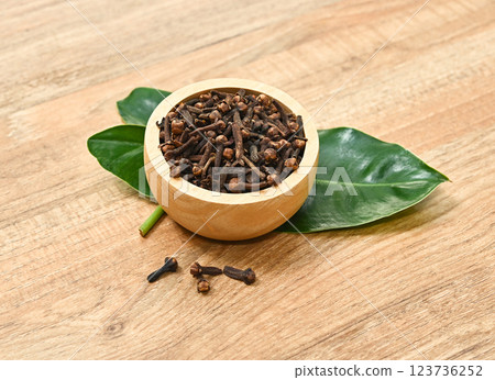 Dried herb, dried cloves in wood bowl  on wood table. 123736252