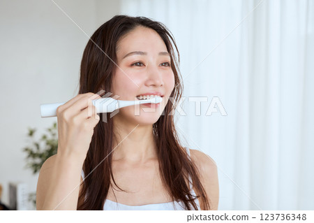 Woman brushing her teeth with an electric toothbrush Woman brushing her teeth with an electric toothbrush 123736348