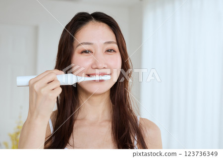 Woman brushing her teeth with an electric toothbrush 123736349