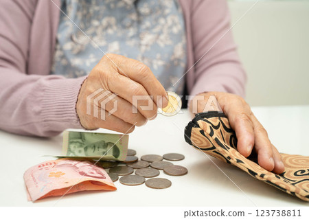 Asian senior or elderly old lady woman holding counting coin money in bag. Poverty, saving problem in retirement. 123738811