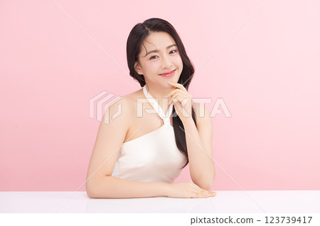 A beautiful young Asian woman with clean, fresh skin against a pink background. Skincare, facial treatment, cosmetology, beauty, and spa. An elegant portrait of an Asian woman. 123739417