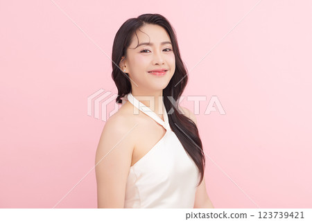 A beautiful young Asian woman with clean, fresh skin against a pink background. Skincare, facial treatment, cosmetology, beauty, and spa. An elegant portrait of an Asian woman. 123739421