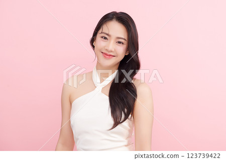 A beautiful young Asian woman with clean, fresh skin against a pink background. Skincare, facial treatment, cosmetology, beauty, and spa. An elegant portrait of an Asian woman. 123739422