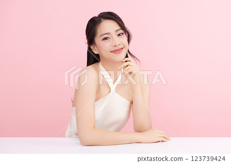 A beautiful young Asian woman with clean, fresh skin against a pink background. Skincare, facial treatment, cosmetology, beauty, and spa. An elegant portrait of an Asian woman. 123739424
